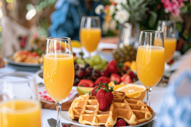 https://www.californiachampagnesabers.com/wp-content/uploads/2026/03/Mimosa-glasses-with-waffles-strawberries-and-fresh-fruit-on-a-brunch-table.png