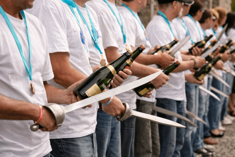 https://www.californiachampagnesabers.com/wp-content/uploads/2026/04/Group-of-people-holding-champagne-bottles-and-sabers-during-a-mass-sabrage-event.png