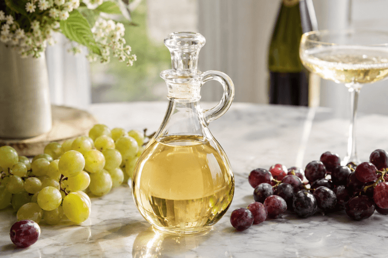 https://www.californiachampagnesabers.com/wp-content/uploads/2026/05/Glass-cruet-of-Champagne-vinegar-on-a-marble-surface-with-green-and-red-grapes-a-Champagne-bottle-and-a-coupe-glass.png